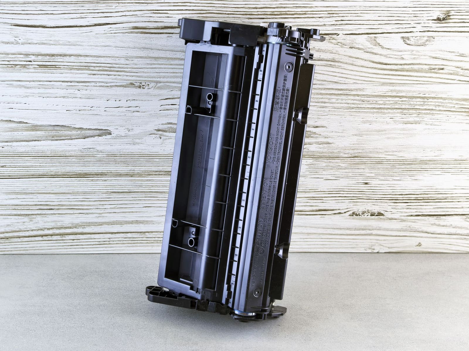 Zwarte tonercartridge rechtop tegen een houten achtergrond